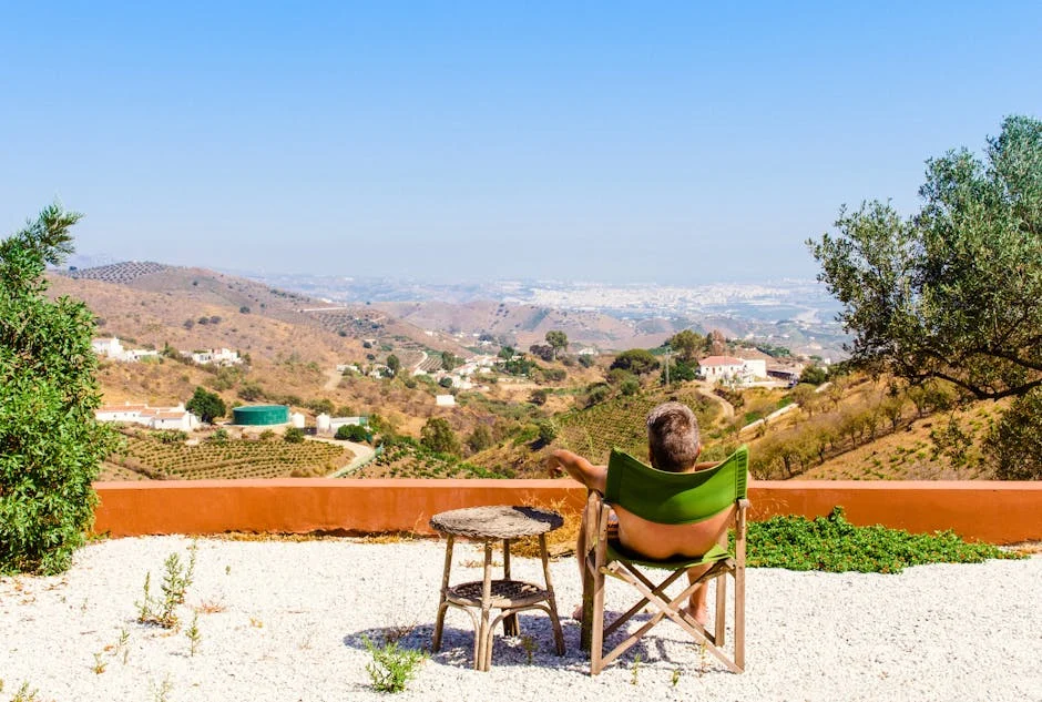 Man relaxing on a terrace, overlooking Córdoba's scenic hills and valleys under a sunny sky.