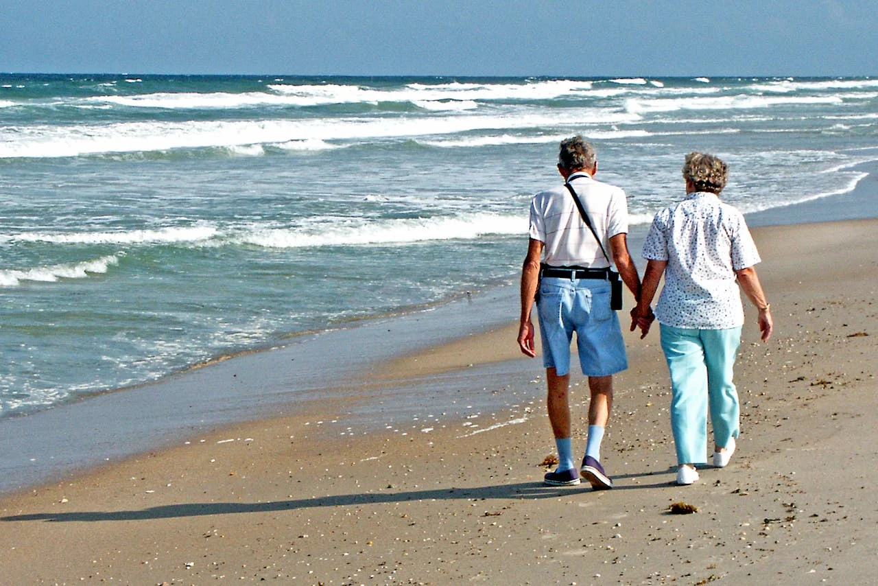 Twee senioren lopen op het strand in Spanje